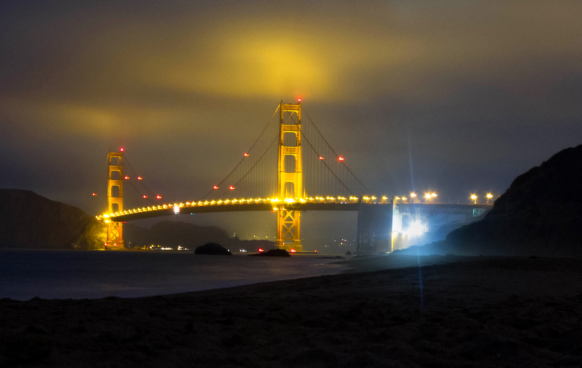 San Francisco's Golden Gate Bridge reflects against the low-lying clouds over Half Moon Bay before dawn.