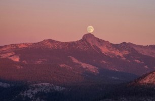 The moon seems to rest on a peak as it rises over Yosemite Valley just before sunset.