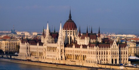 The Parliament Building in Budapest, Hungary is illuminated by the sun setting across the Danube River.